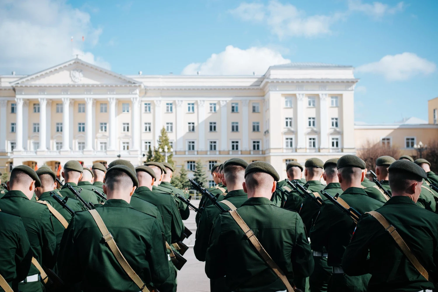 Uniformed cadets assembled in front of a white columned academic building