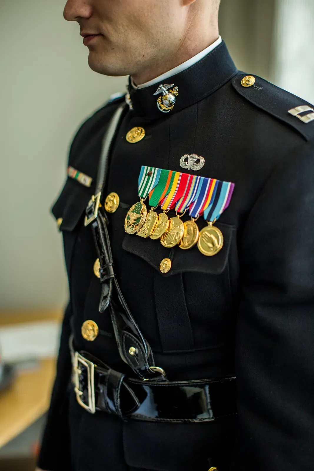 Officer in a dark dress blue uniform with medals and white belt