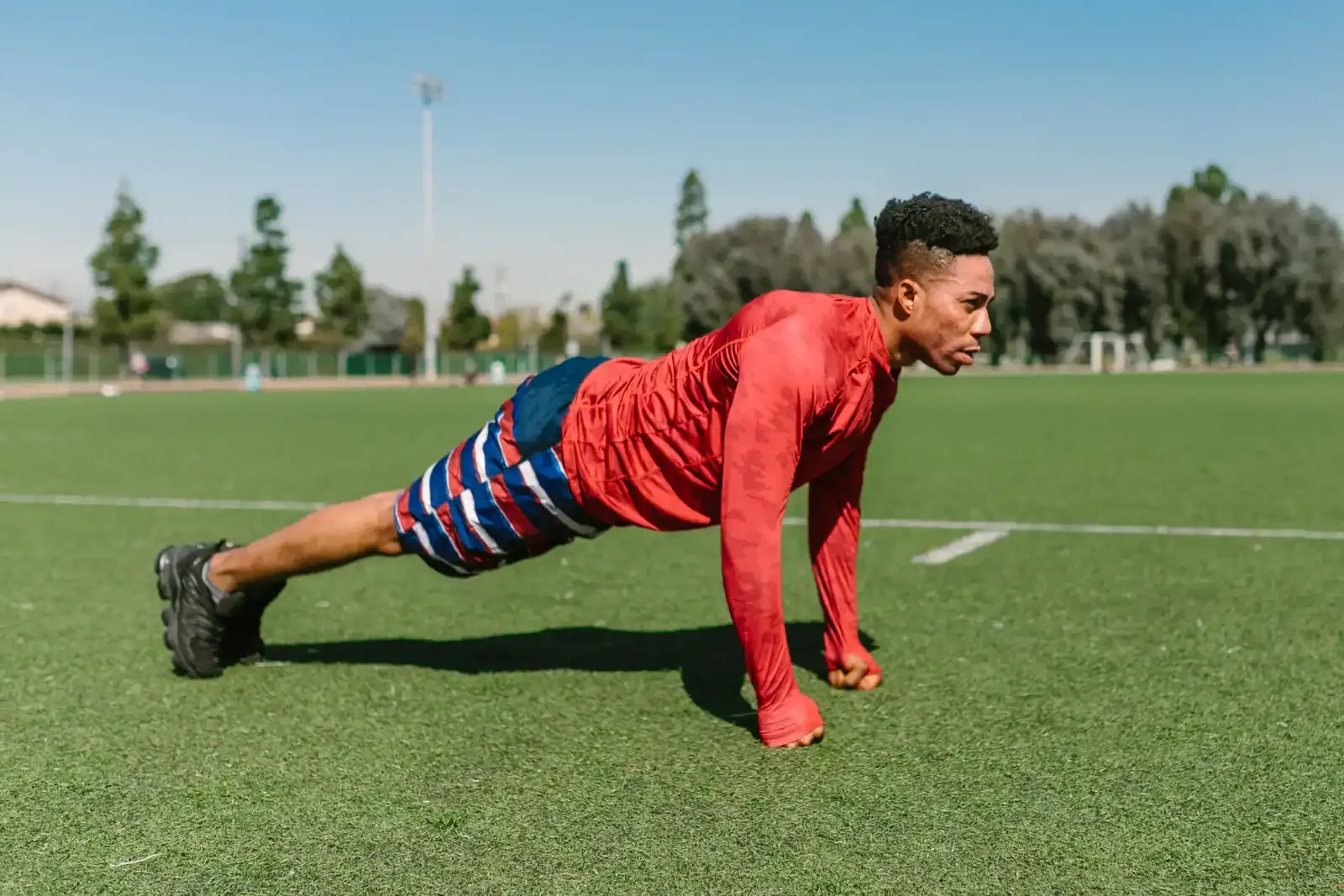 Man doing push-ups on a grass field during outdoor training