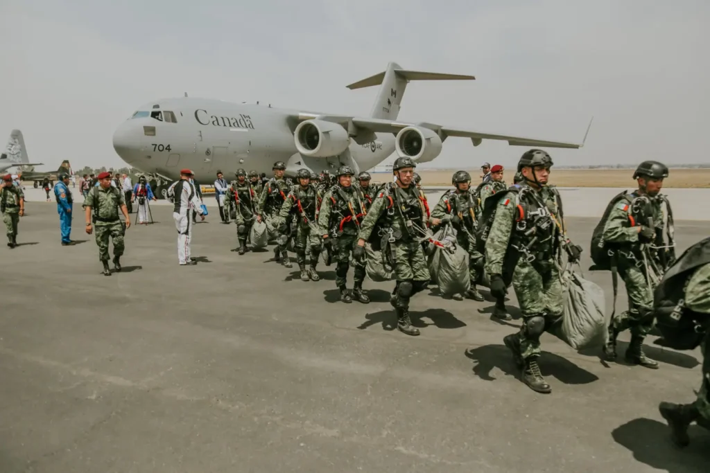 Soldiers with rucksacks walking toward a military transport aircraft