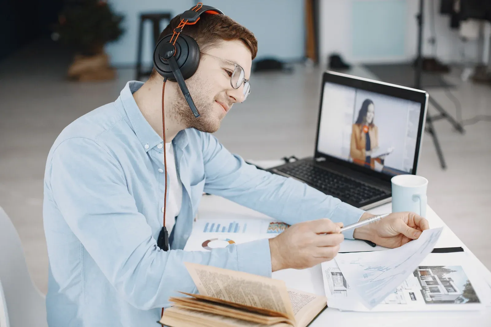 Student wearing headphones taking notes in front of a laptop
