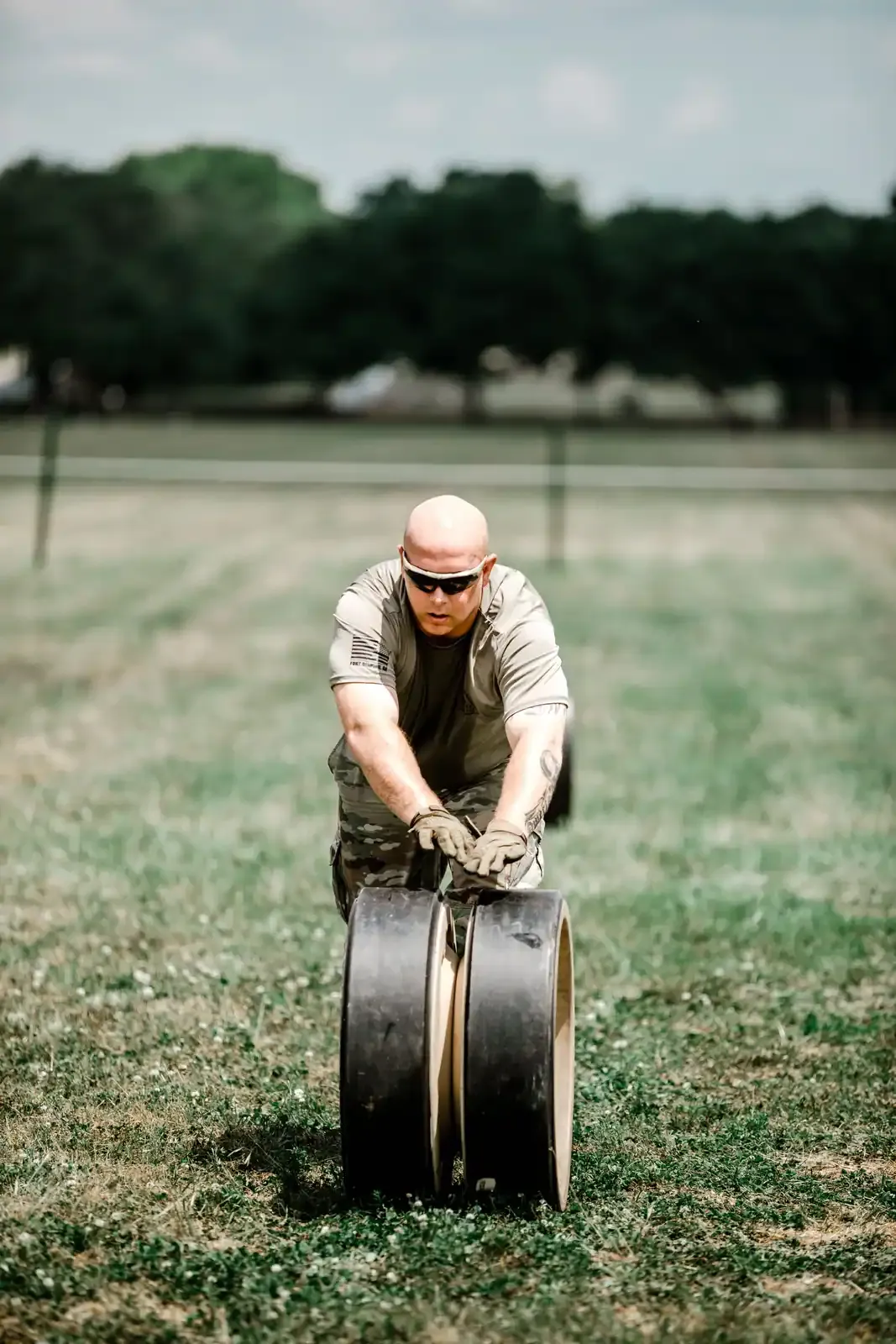 Trainee rolling a heavy tire across a field during physical training