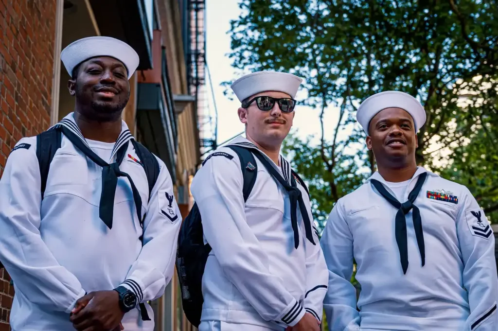 Three U.S. Navy sailors in white uniforms and white sailor caps